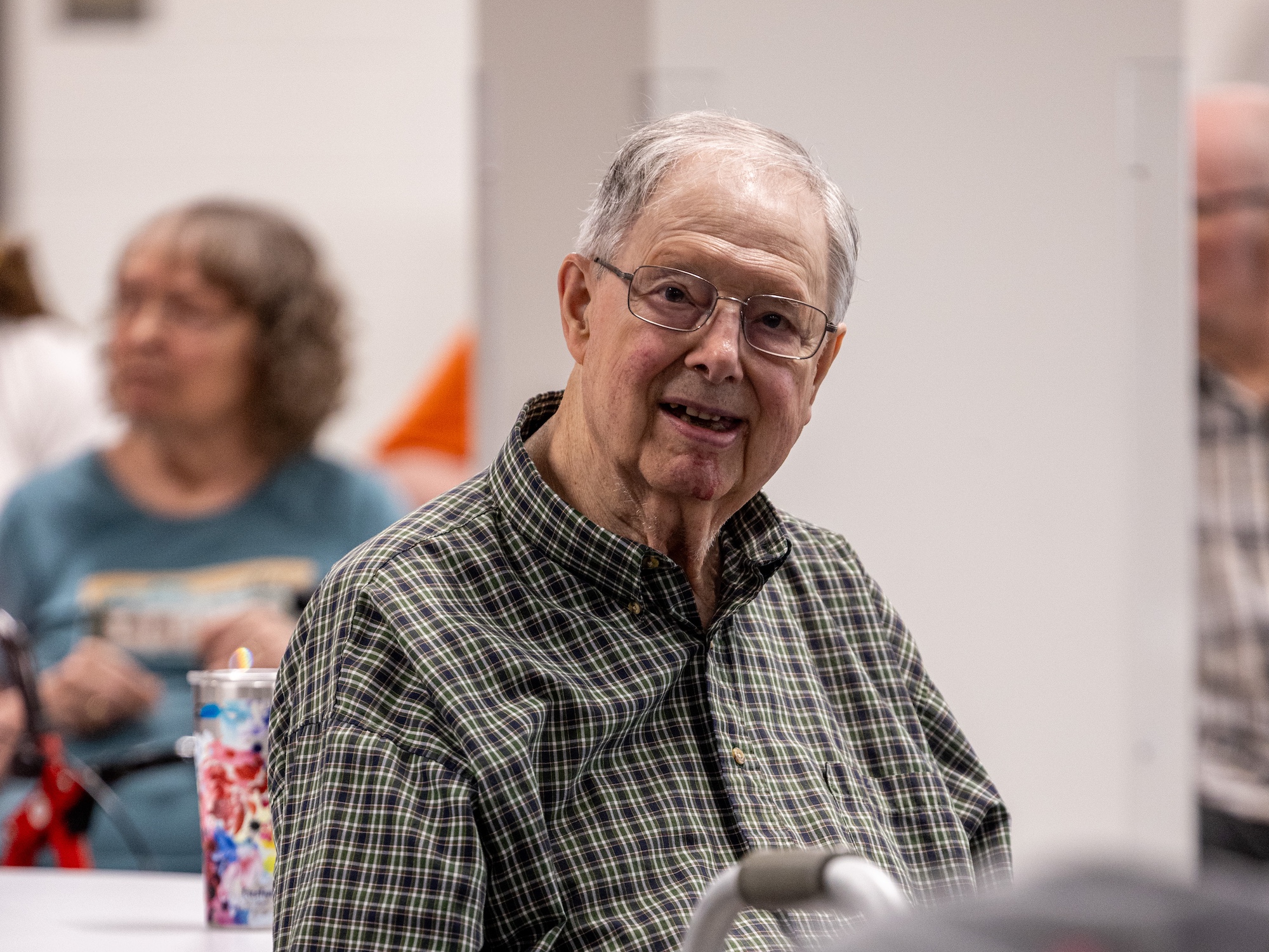 An elderly gentleman in a pattern collared shirt smiles at the camera during a session with Curative Connections.