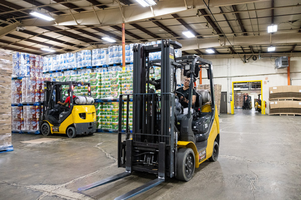 People driving forklifts around a warehouse