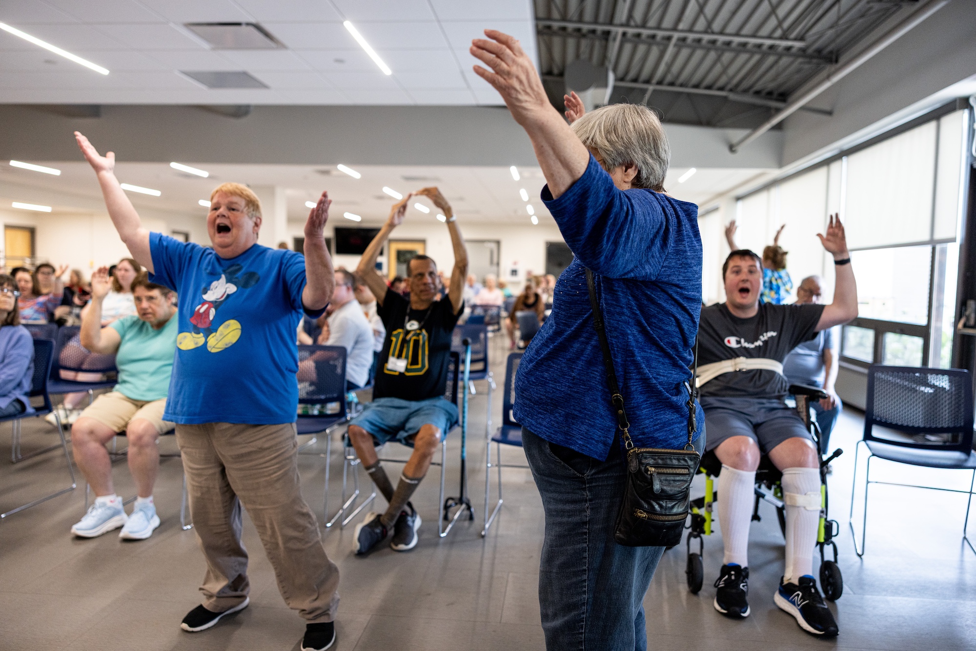 A group of people at Curative Connections raise their hands while enjoying music together.