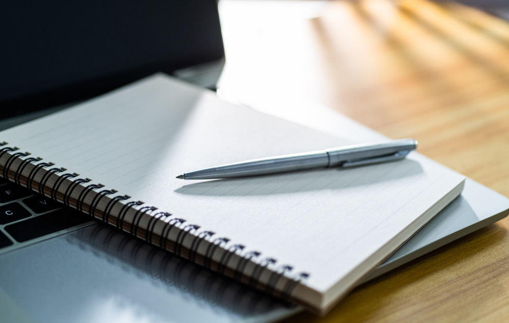 A blank page in a notebook with a pen on top