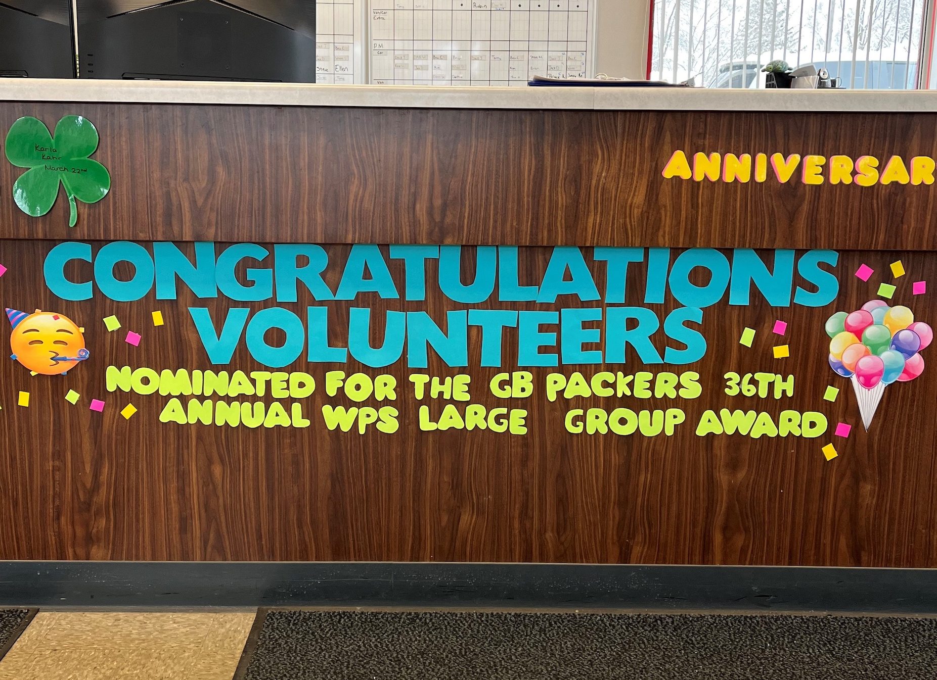 A message on the front desk of Curative Connections reads in paper letters "Congratulations Volunteers Nominated for the GB Packers 36th Annual WPS Large Group Award"