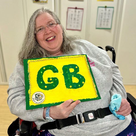 Curative Connections participant Amy holding a craft she made to show her support for the Green Bay Packers.