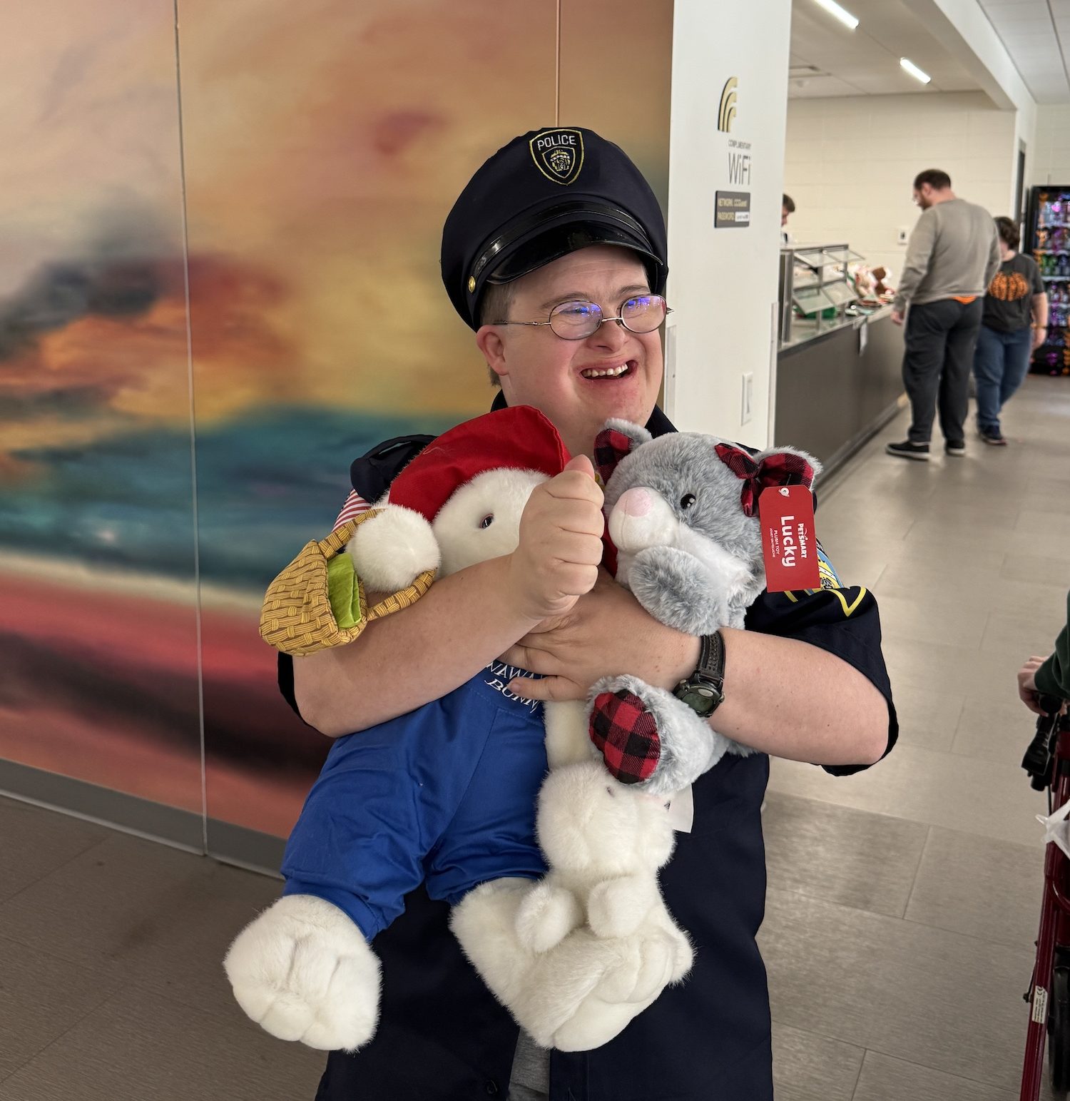 A man clutches a couple stuffed animals while wearing a police officer hat while attending Curative Connections.